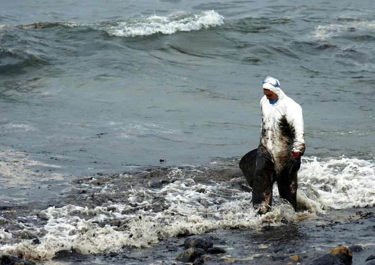 Foto tirada em 2 de dezembro de 2002 mostra voluntário caminhando pela praia Muxia após o vazamento de petróleo do navio 