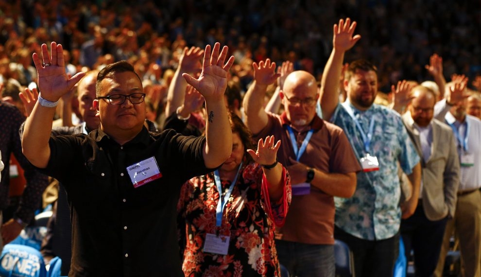 Membros da Convenção Batista do Sul e convidados erguem as mãos em oração durante a reunião anual da convenção em Birmingham, Alabama.