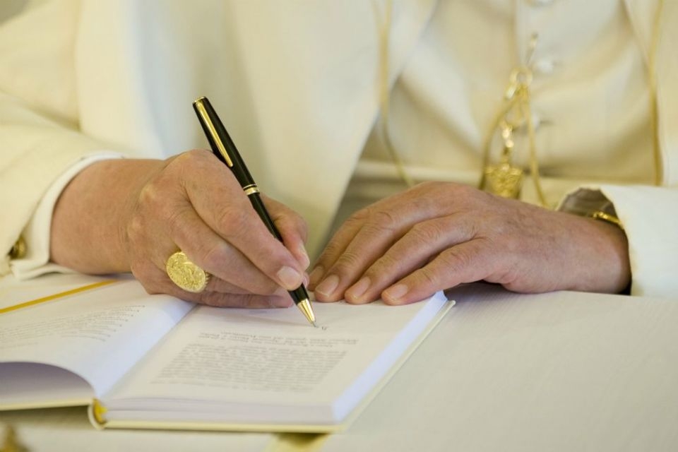 O papa Bento XVI assina uma cÃ³pia de sua encÃ­clica 'Caritas in Veritate', no Vaticano em 6 de julho de 2009, que aborda a crise econÃ´mica global.