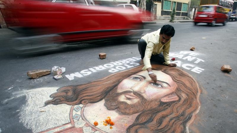 O pintor indiano Swapan Das dá o toque final a um retrato de Jesus Cristo em uma via movimentada na cidade indiana de Calcutá, no dia 24 de dezembro de 2008