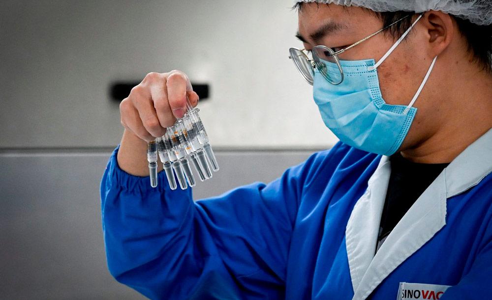 Funcionário da Sinovac, farmacêutica chinesa que tem parceria com o Instituto Butantan, observa vacinas Coronavac