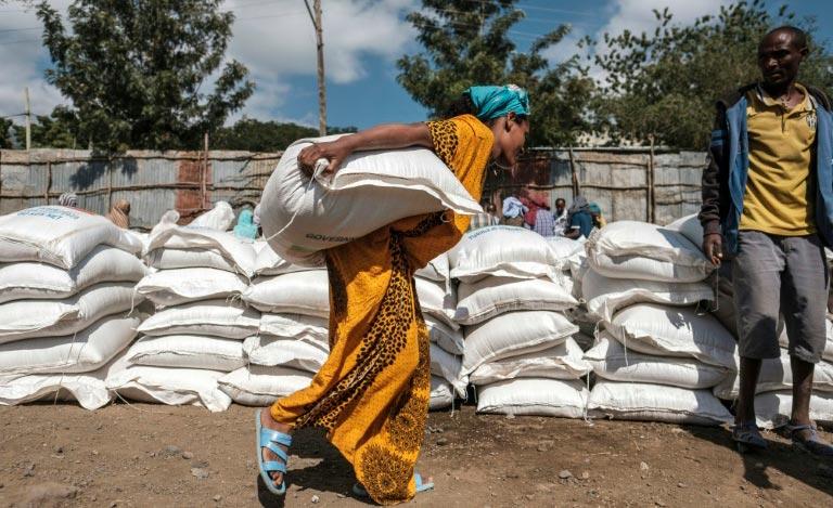 Mulher carrega saco de chá, após distribuição de ajuda humanitária do governo etíope, em Alamata