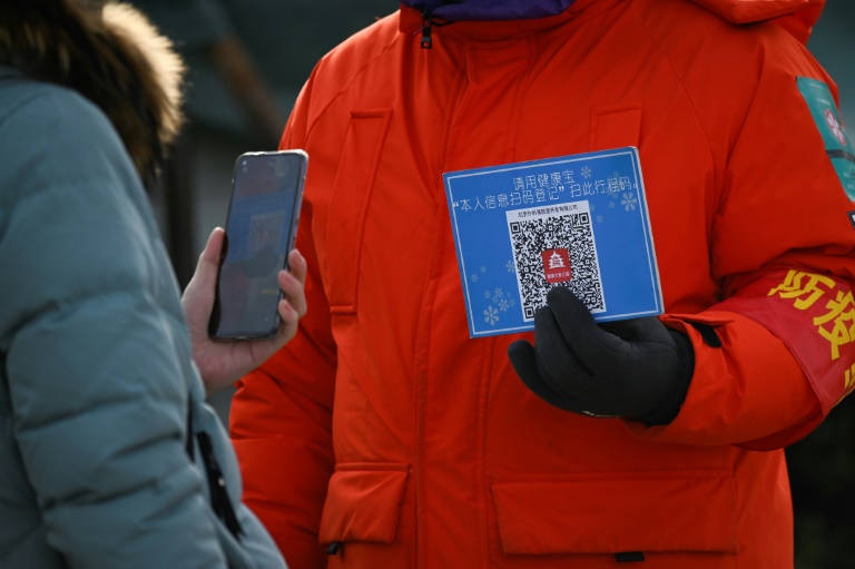 Uma mulher usa seu telefone celular para ler um código QR para registro de saúde antes de entrar em uma pista de gelo ao ar livre em Pequim em 12 de janeiro de 2021