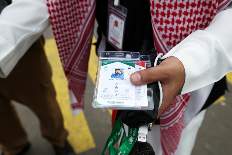 Membro da equipe saudita verifica os cartões do hajj dos peregrinos, permitindo o acesso sem contato a locais religiosos, acomodação e transporte