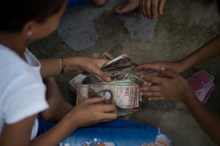 Crianças jogam cartas apostando cédulas venezuelanas em Puerto Concha, na   Venezuela