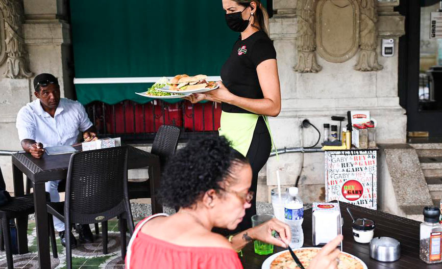 Garçonete serve clientes em restaurante em Havana: alta de preços e falta de alimentos