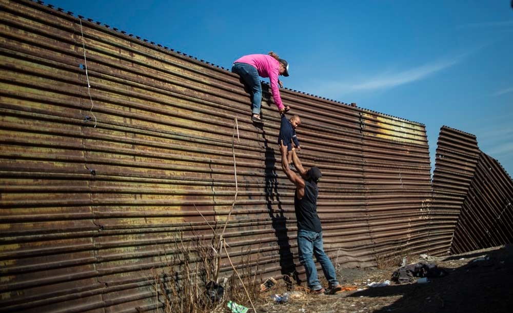 Migrantes pulam cerca na fronteira entre o México e os EUA
