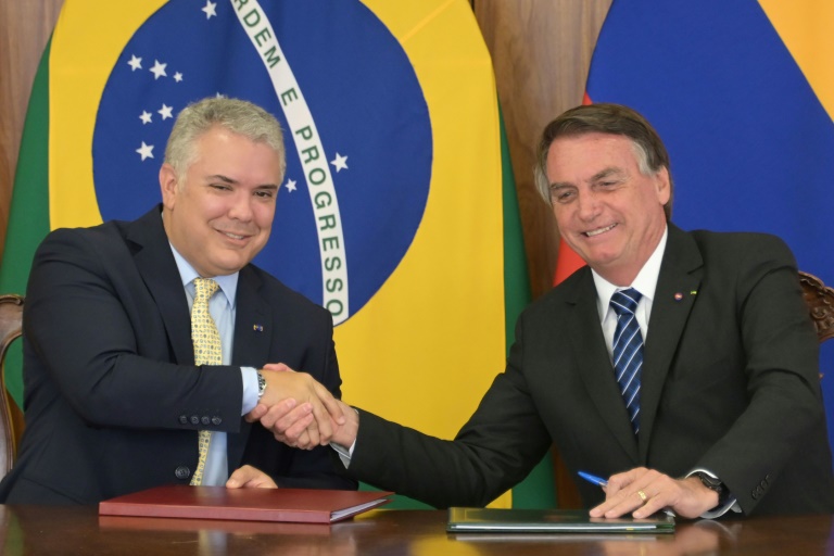 O presidente da Colômbia, Ivan Duque (E) e seu homólogo brasileiro Jair Bolsonaro se cumprimentam durante a assinatura de acordos no Palácio do Planalto, em Brasília, em 19 de outubro de 2021