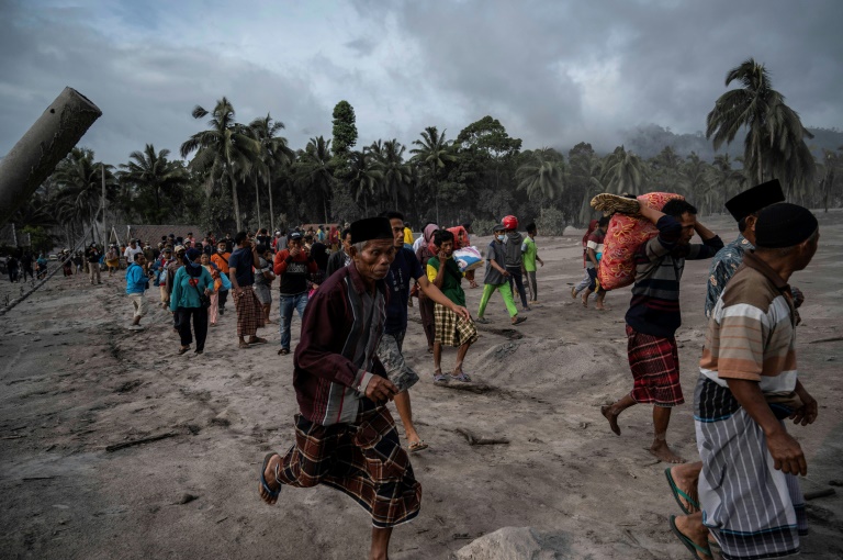 Moradores fogem da erupção do vulcão Semeru em uma paisagem coberta de cinzas, na região de Lumajang, na Indonésia, 5 de dezembro de 2021