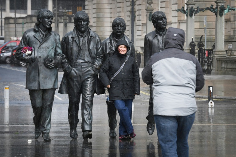 Pessoas posam para fotos na estátua dos Beatles em Liverpool, noroeste da Inglaterra, em 10 de dezembro de 2021