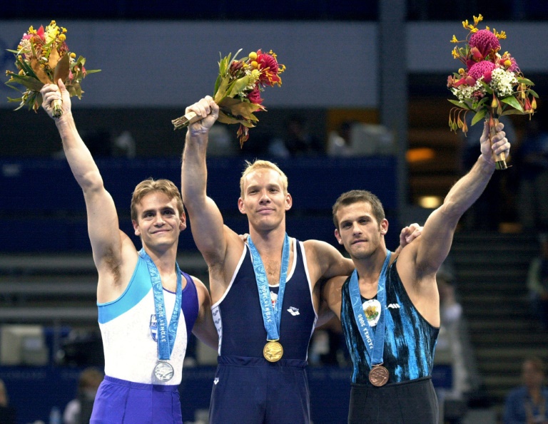 Szilveszter Csollany (centro), que morreu de Covid-19, no pódio das argolas nos Jogos Olímpicos de Sydney-2000 juntamente com Dimosthenis Tampakos (E) e Yordan Yovchev (D)
