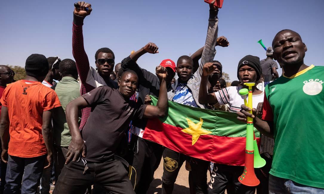 Moradores de Burkina Faso com bandeira do país vão às ruas da capital Uagadugu para apoiar os militares
