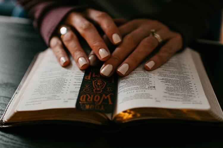 Uma mulher descansa as mãos nas páginas abertas de uma Bíblia.