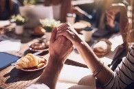 Mesa com comida e pessoas de mãos dadas dando graças (iStock)