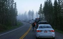 Veículos fazem fila antes do amanhecer para entrar no setor sul do Parque Nacional de Yellowstone, Estados Unidos, em 22 de junho de 2022. (GEORGE FREY/AFP)