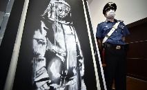 (ARQUIVO) Nesta foto de arquivo tirada em 11 de junho de 2020 um policial vigia uma obra de arte atribuída a Banksy, que foi roubada no Bataclan em Paris em 2019 (Filippo MONTEFORTE/AFP)