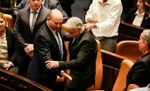 O ministro israelense das Relações Exteriores, Yair Lapid (D), e o primeiro-ministro demissionário Naftali Bennett trocam de cadeira no Knesset após a dissolução do Parlamento (Menahem KAHANA/AFP)