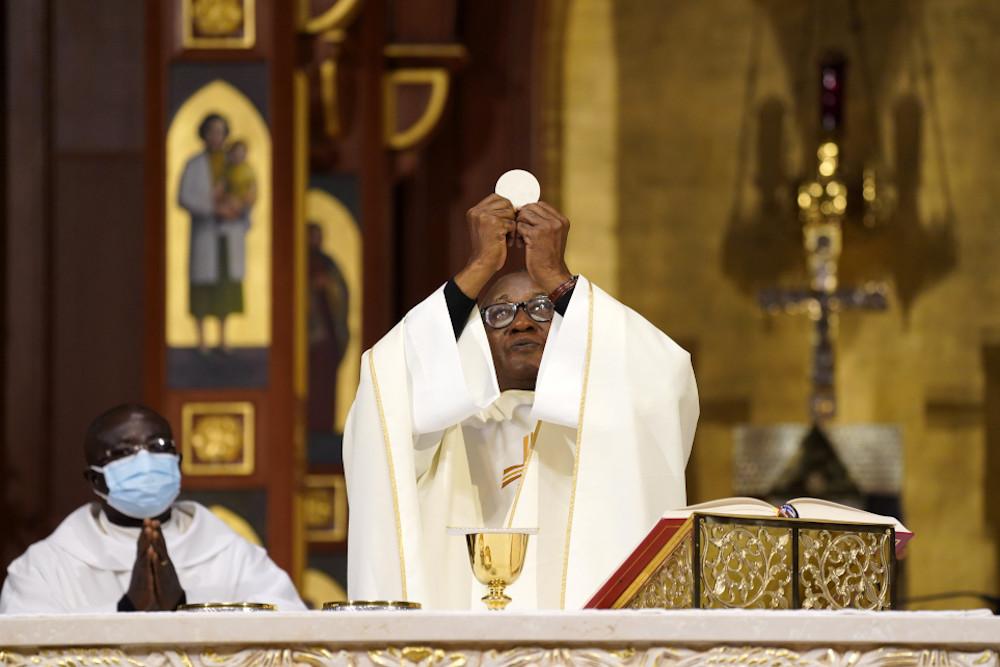 Pe. Eden Jean Baptiste eleva a Eucaristia enquanto celebra uma missa para católicos de ascendência haitiana na Catedral de St. Agnes em Rockville Center, Nova York, 1º de janeiro de 2022, a festa de Maria, Mãe de Deus